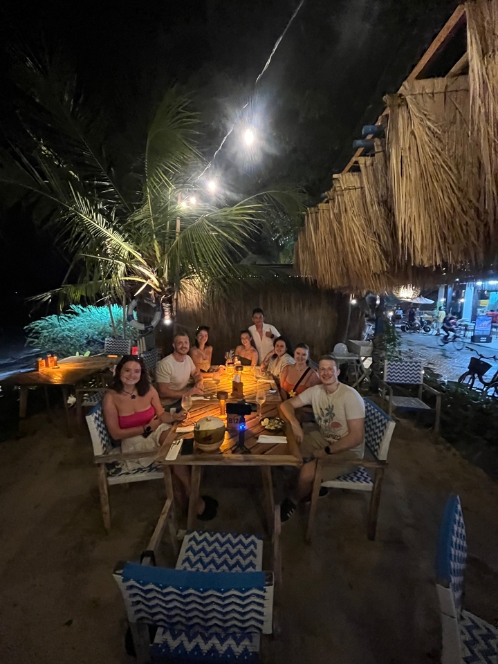 Un groupe de personnes dînant dans un restaurant en bord de mer la nuit.