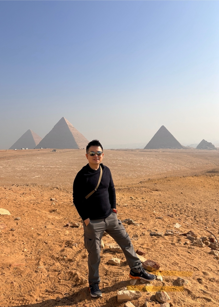 Personne qui pose avec les pyramides de Gizeh en arrière-plan.