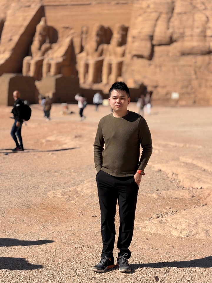 Personne debout dans un espace ouvert avec des ruines au loin.