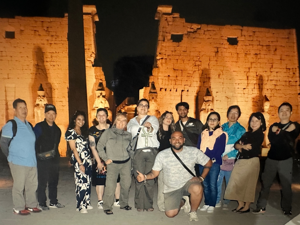 Photo de groupe la nuit devant les ruines d'un temple égyptien vivement éclairé.