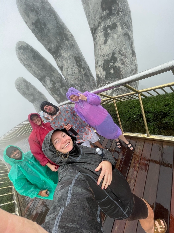 Groupe de personnes en imperméables par jour de brouillard près d'une grande statue de mains.