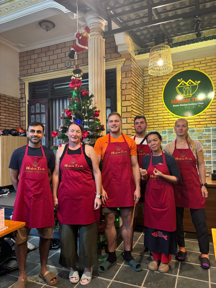 Photo de groupe avec des personnes en tabliers posant à l'intérieur près d'un sapin de Noël.