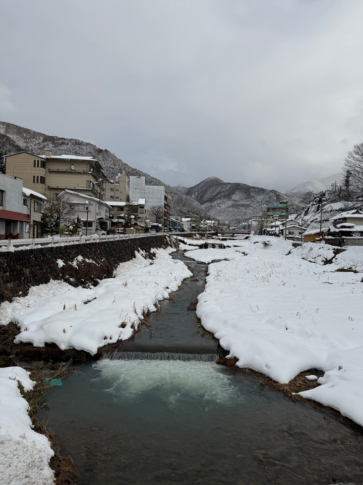 Ville enneigée et rivière avec des montagnes en arrière-plan.