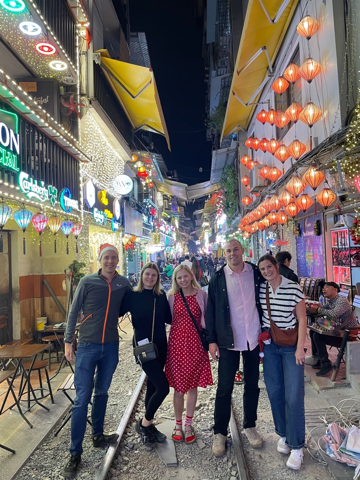 Groupe de personnes posant dans une rue animée éclairée par des lanternes.