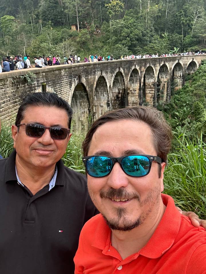 Deux personnes posent devant un pont historique.