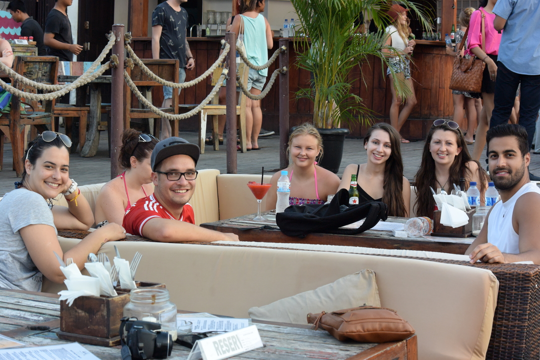 Group of people sitting at a waterfront cafe.