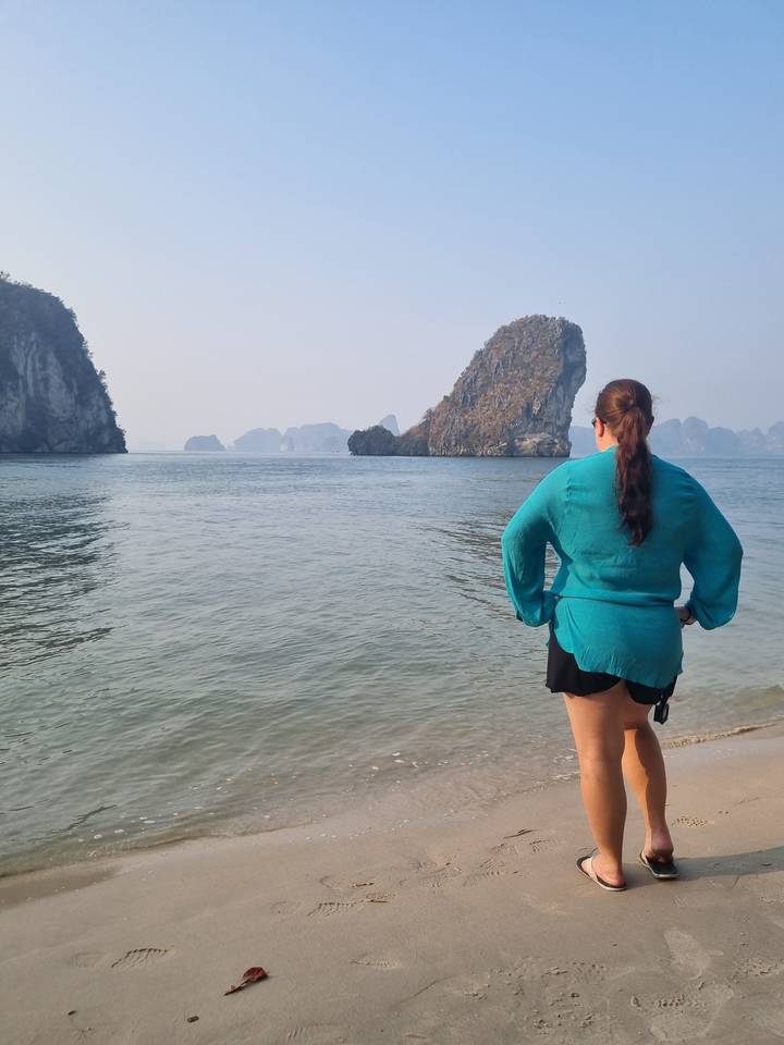 Personne debout sur une plage avec des îles calcaires en arrière-plan.
