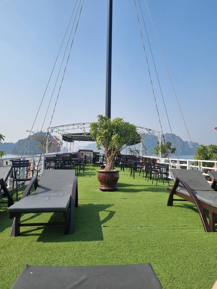 Pont d'un bateau de croisière sur l'eau avec des falaises calcaires en arrière-plan.