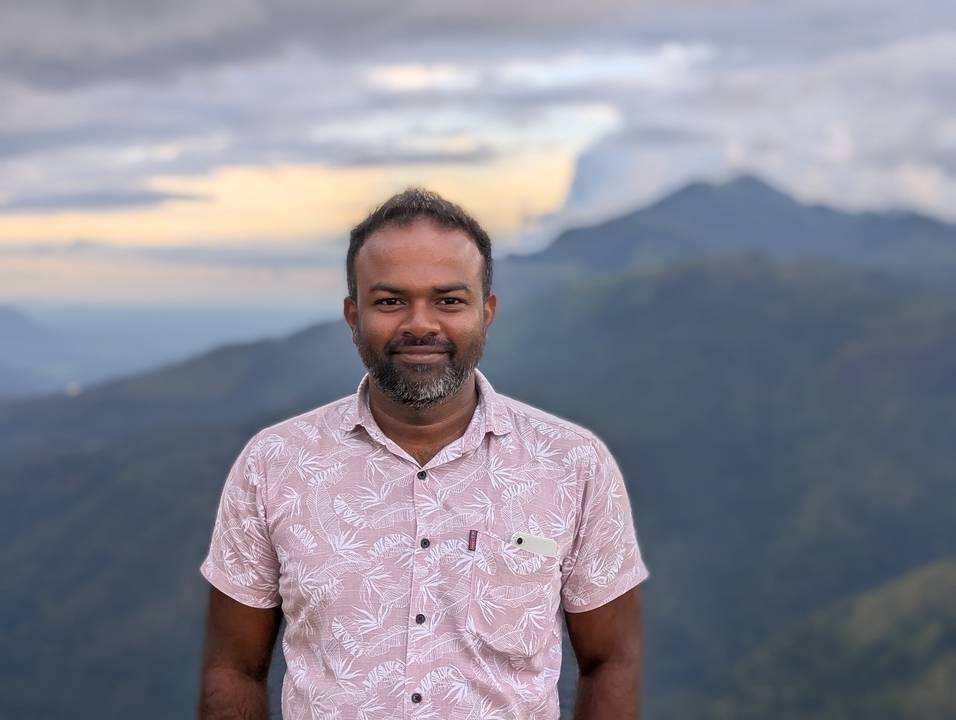 Portrait d'un homme avec des montagnes en arrière-plan au coucher du soleil.