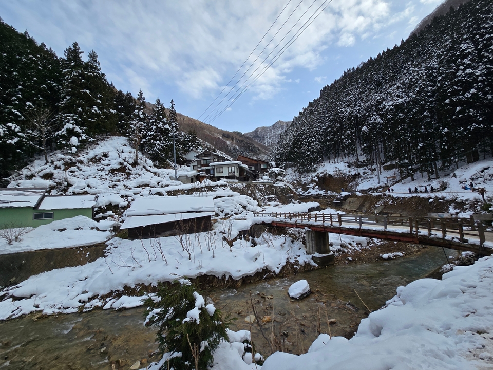 Village de montagne enneigé avec des arbres et une rivière.