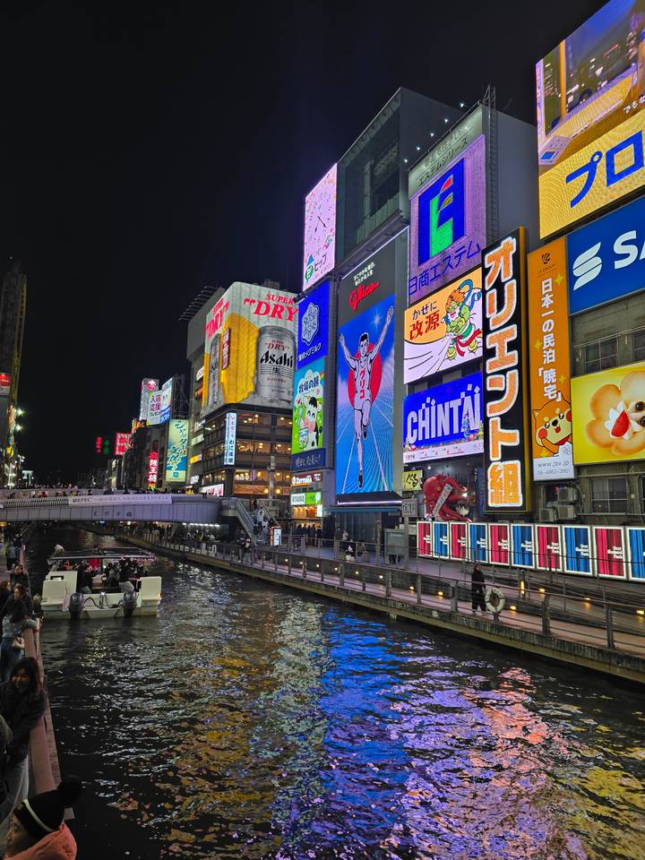Panneaux publicitaires néon vibrants illuminant une rue au bord d'un canal.