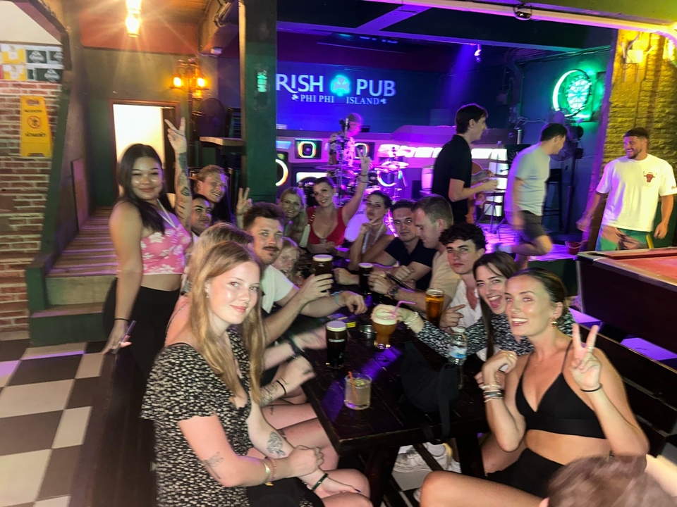 Un groupe qui se rassemble autour d'une table de bar avec des lumières vives et une ambiance sociale.