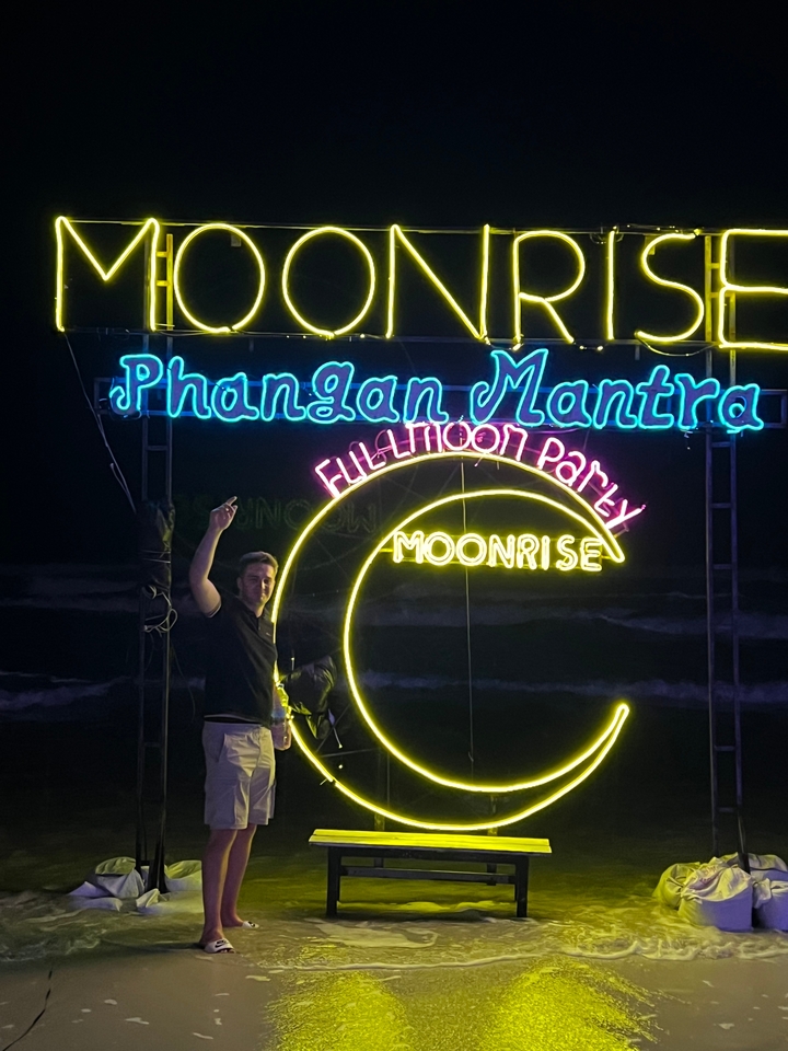 Une personne debout près d'enseignes au néon brillantes pour une fête de pleine lune.