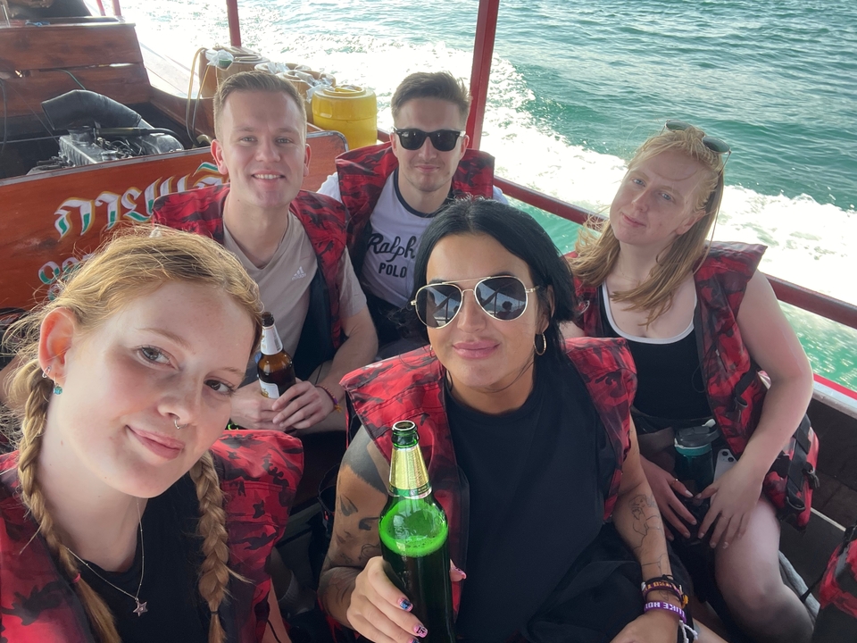 Un groupe d'amis sur un bateau avec des gilets de sauvetage, savourant des boissons.