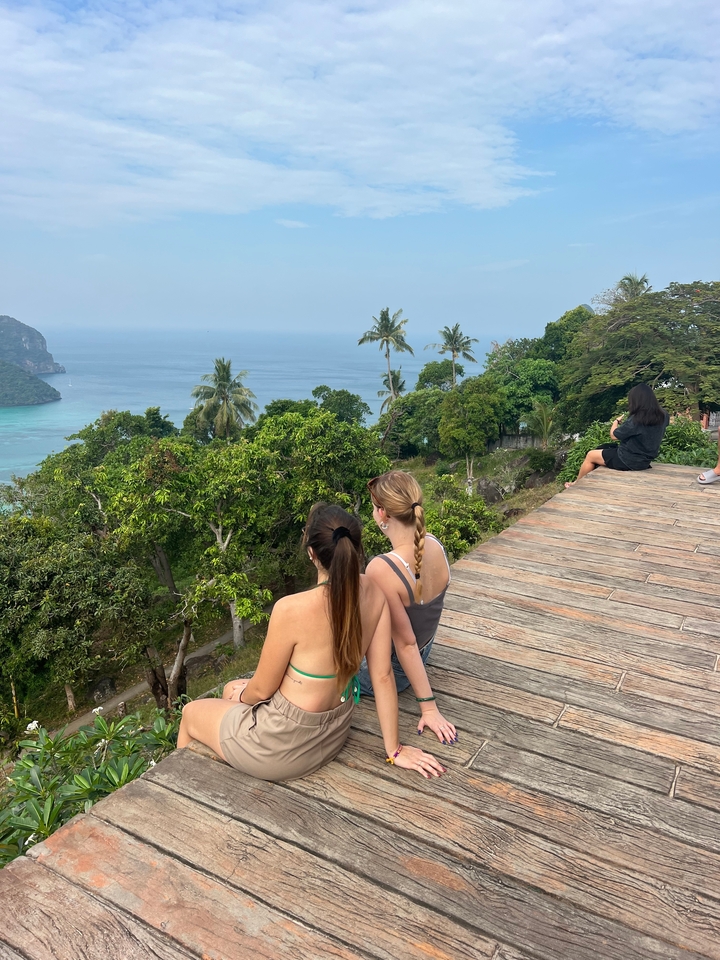 Deux personnes profitant d'une vue panoramique sur l'océan depuis une terrasse en bois.