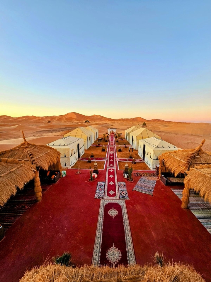 Un campement dans le désert magnifiquement aménagé avec des tentes et un tapis rouge.