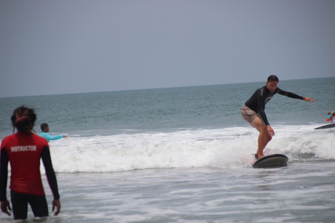 Person surfing on waves with other surfers in the water.