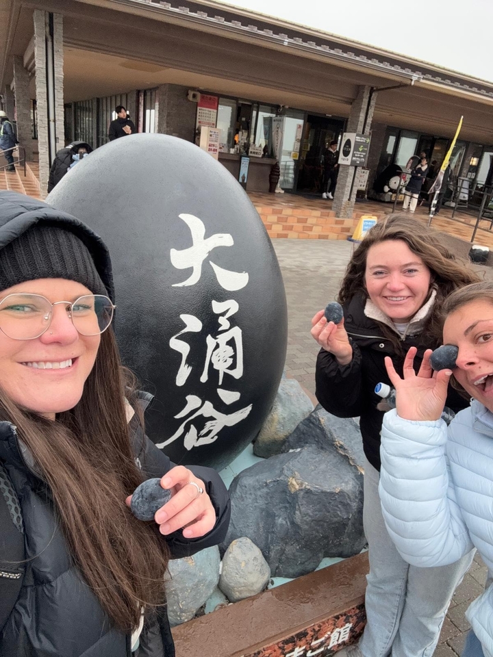 Des femmes posent avec des œufs noirs dans un lieu touristique.