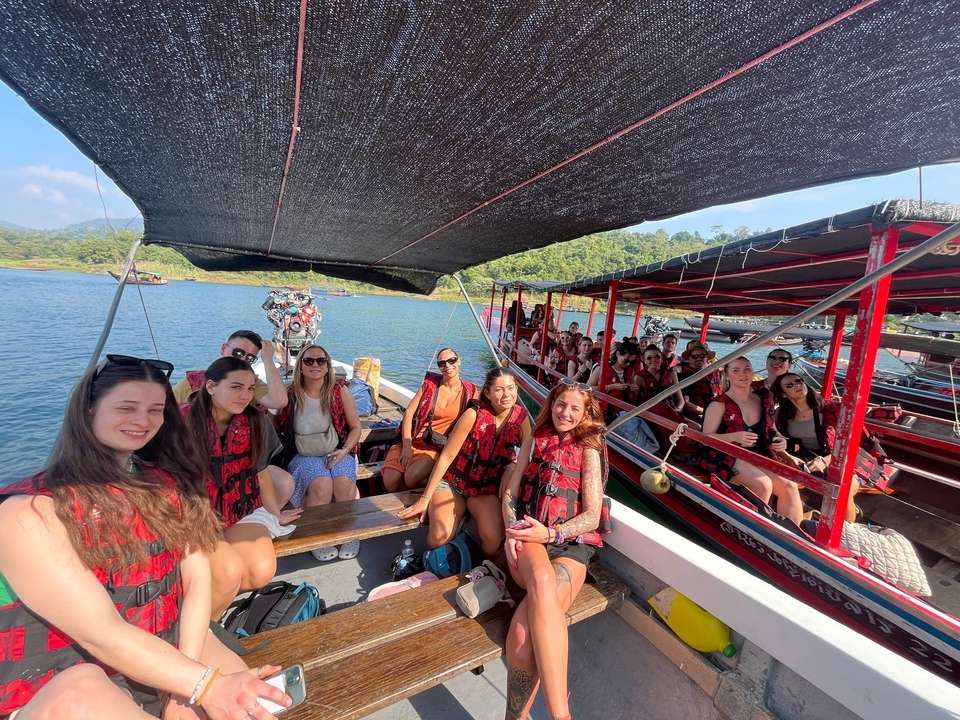 Des personnes sur un bateau portant des gilets de sauvetage avec une vue panoramique sur l'eau et la verdure.