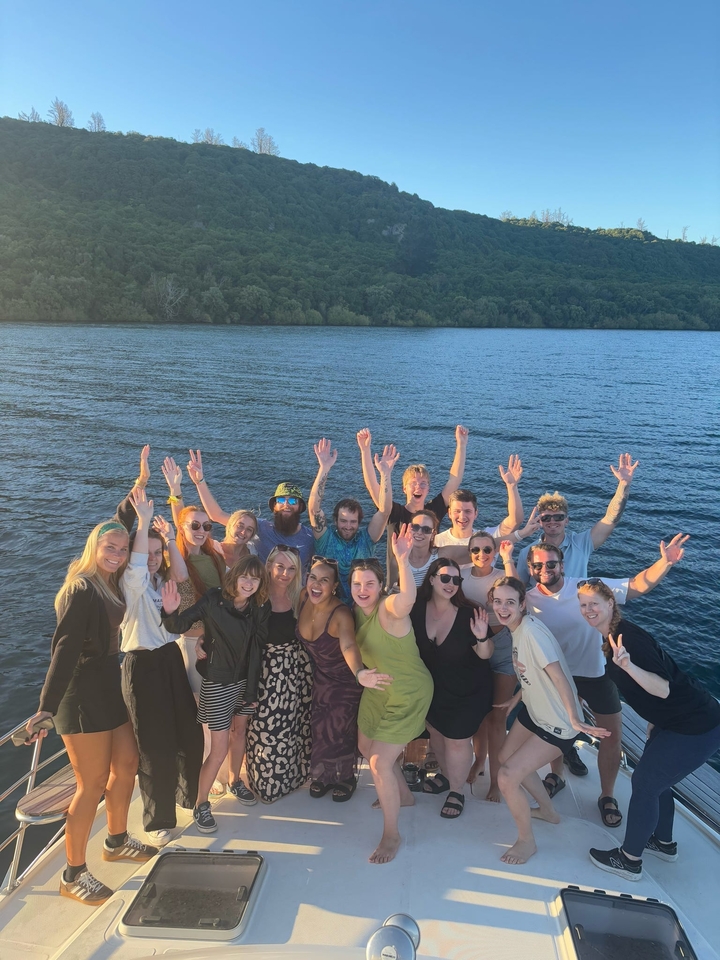 Groupe de personnes qui saluent de la main depuis un bateau sur un lac.