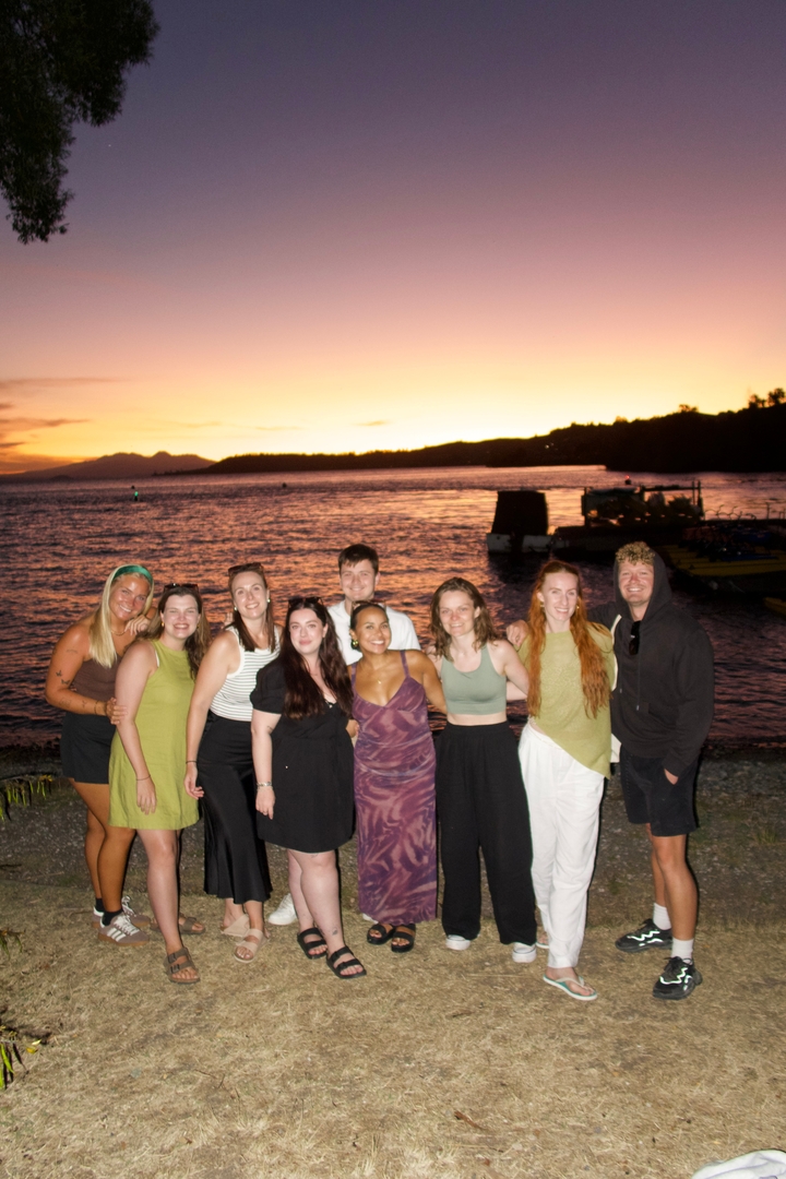 Groupe de personnes posant près d'un lac au coucher du soleil.