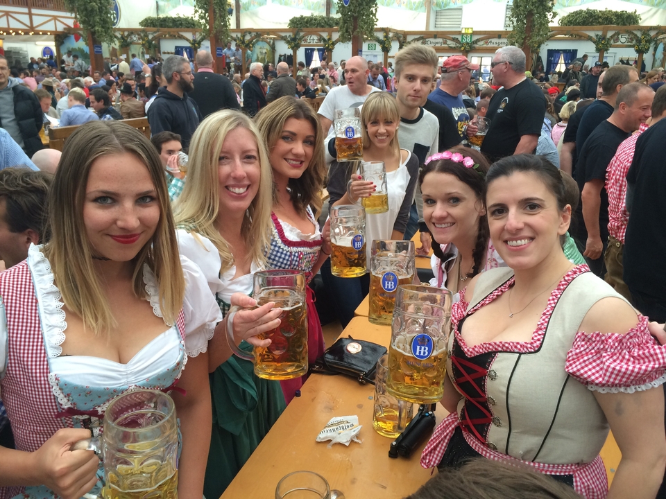 Groupe de femmes en tenue traditionnelle tenant des verres de bière.