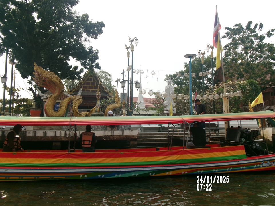 Bateau décoré amarré près d'une zone culturelle avec sculpture de dragon.