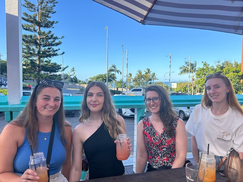 Quatre amis assis qui savourent des boissons à la terrasse d'un café.