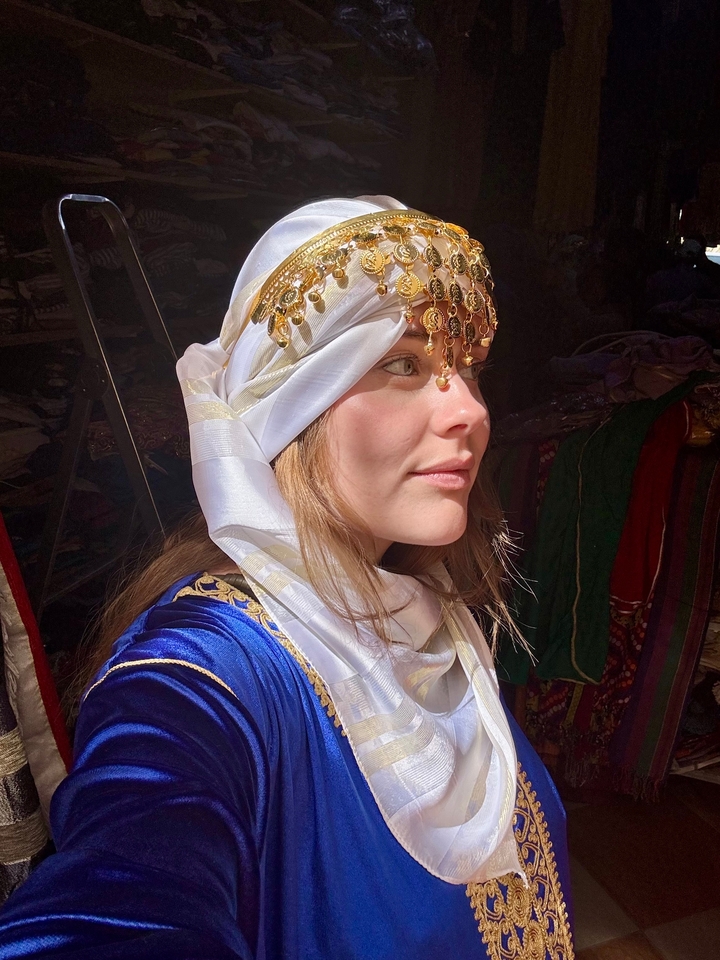 Person, die traditionelle Kleidung mit dekorativem Kopfschmuck trägt.