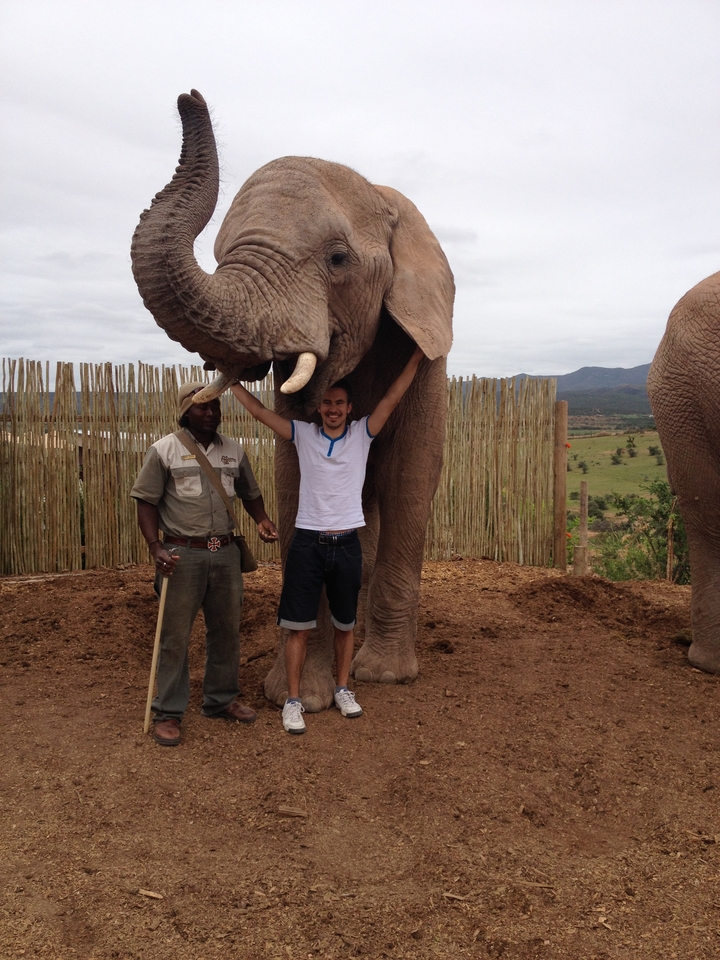 Deux personnes posant avec un éléphant dans un parc animalier.