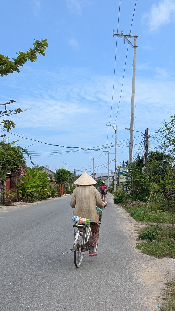 Une personne marchant le long d'une route avec de la verdure et des lignes électriques.