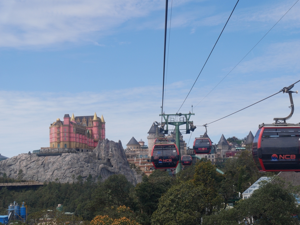 Téléphériques se dirigeant vers un parc d'attractions ressemblant à un château.