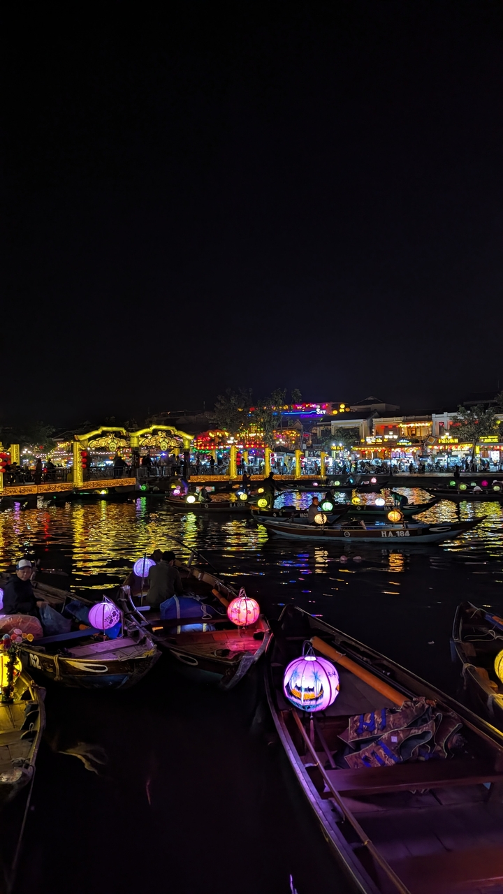 Scène de nuit avec un pont illuminé et des bateaux sur l'eau.