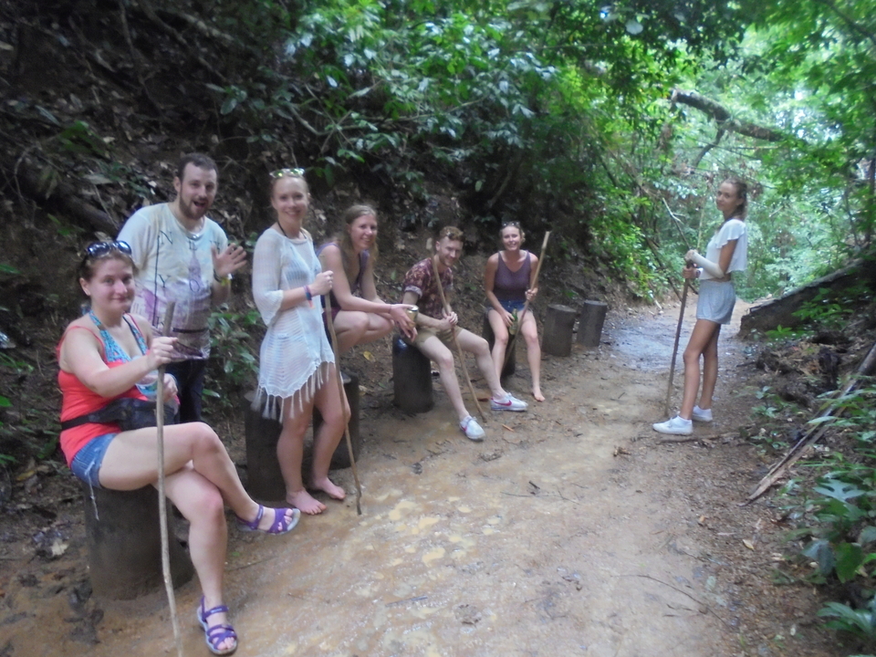 People resting with walking sticks in a forest trail.