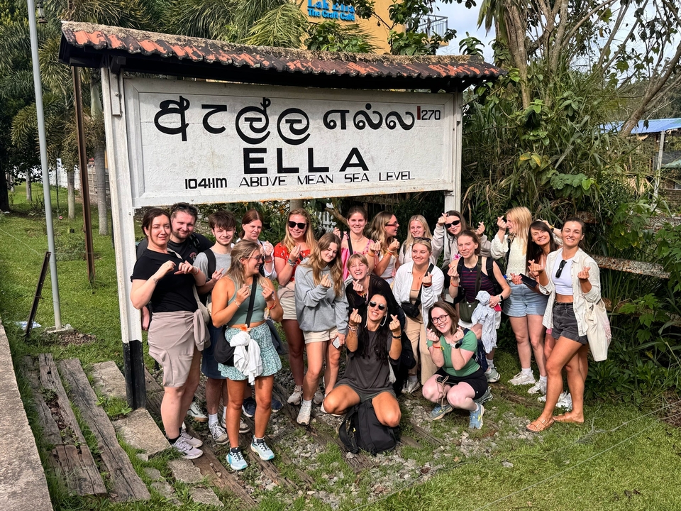 Un groupe de touristes posant devant un panneau pour Ella.