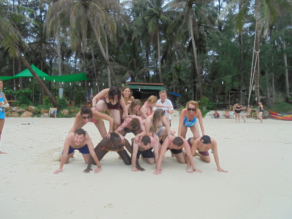 People forming a human pyramid on the beach.