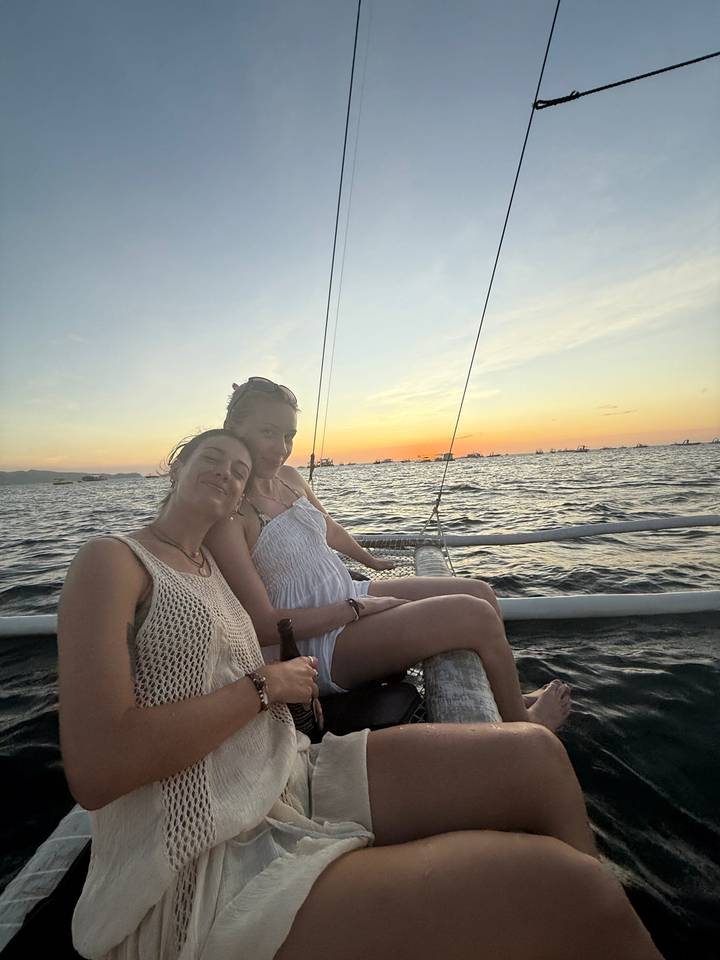 Deux femmes sur un bateau avec un coucher de soleil en arrière-plan.