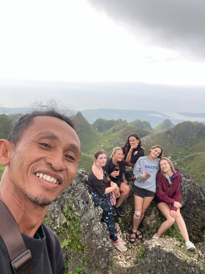 Groupe de personnes posant sur une montagne avec une vue panoramique.