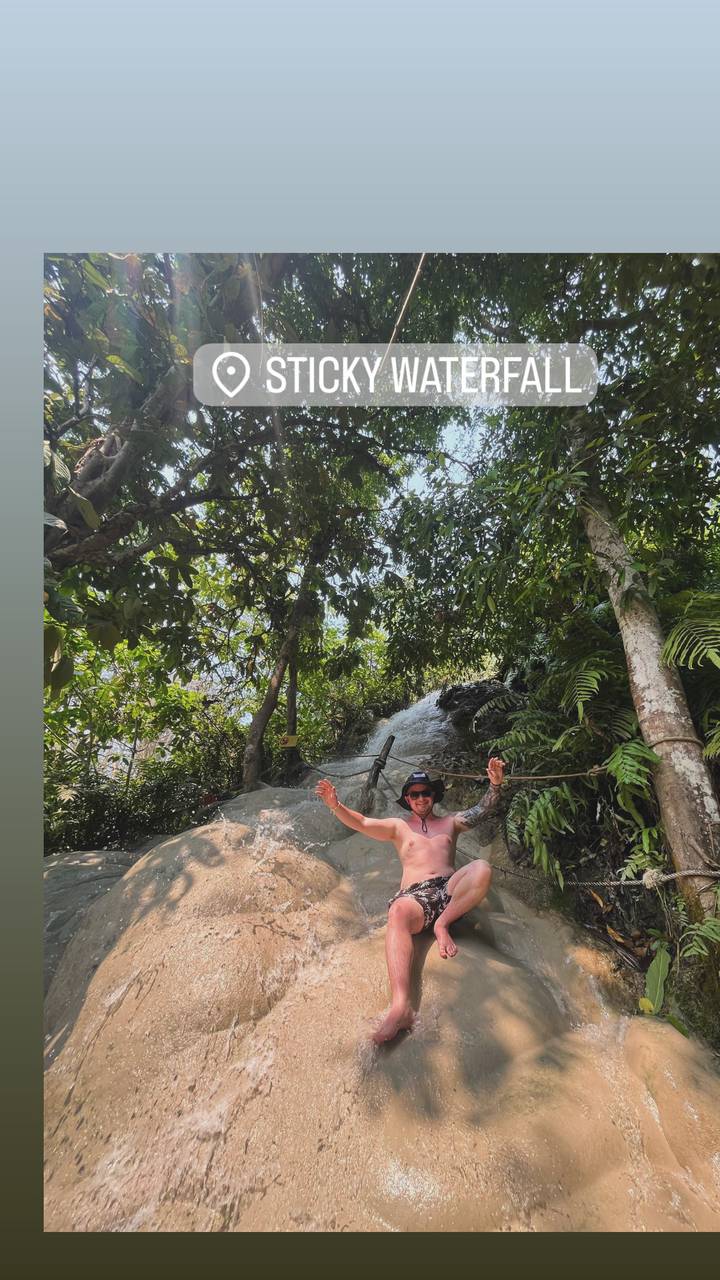 Personne souriante tenant une corde dans un environnement de jungle.