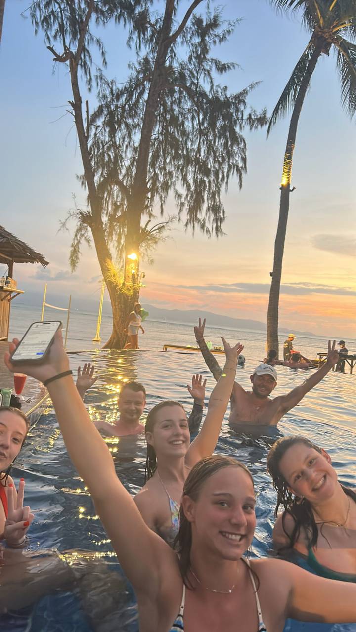 Groupe de personnes dans une piscine avec un coucher de soleil en arrière-plan.