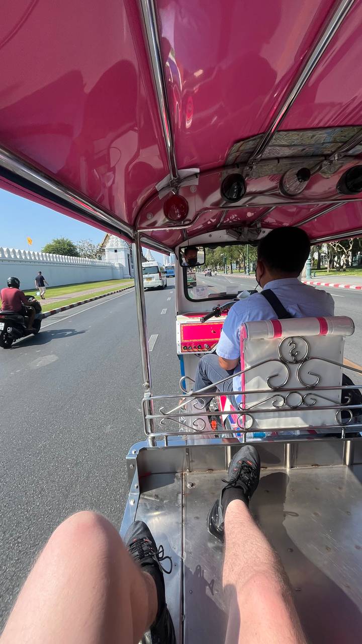 Personne se déplaçant en tuk-tuk dans une rue animée.