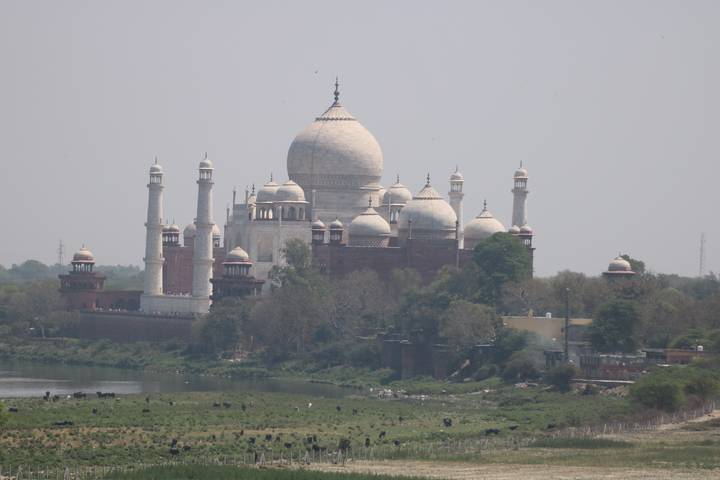 Une vue lointaine du Taj Mahal de l'autre côté d'une rivière.