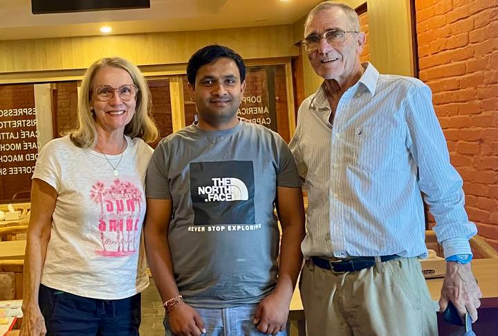 Trois personnes posent à l'intérieur d'un restaurant avec des intérieurs en bois.