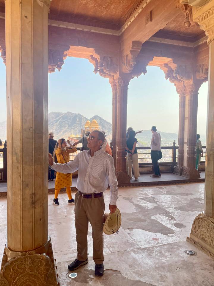 Des gens admirent la vue depuis un bâtiment historique avec des montagnes en arrière-plan.