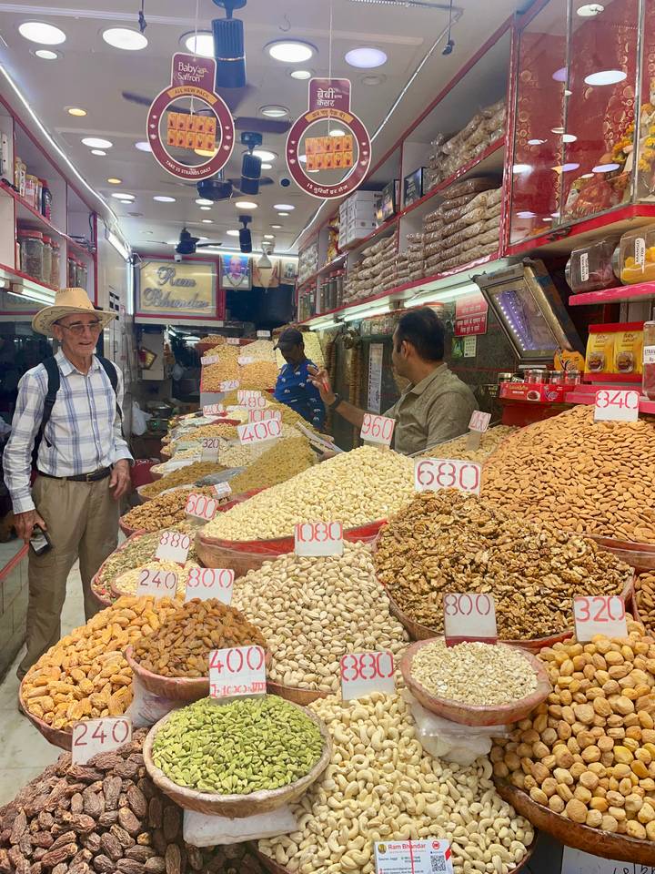 Homme dans un marché avec une variété de noix et d'épices en exposition.
