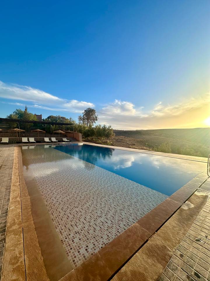 Ein Infinity-Pool mit Blick auf eine malerische Landschaft bei Sonnenuntergang.