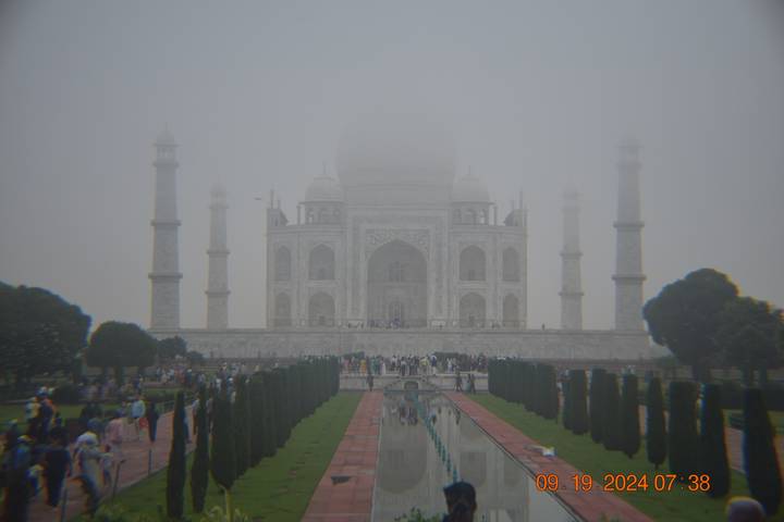 Le Taj Mahal enveloppé de brume avec des touristes au premier plan.