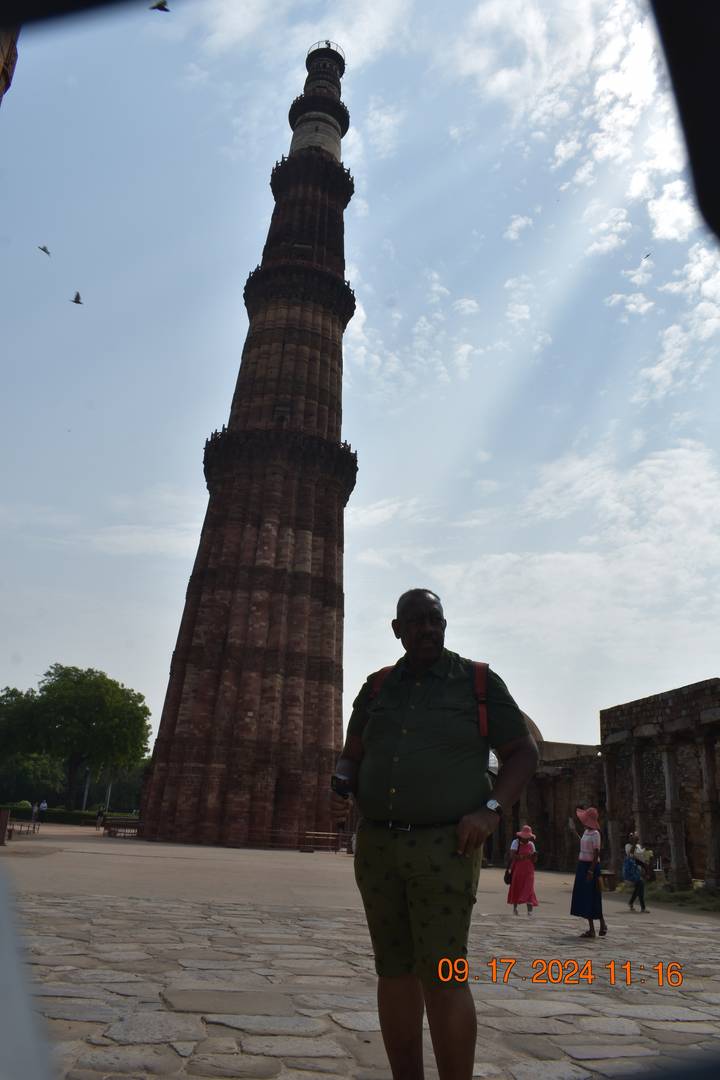 Une personne en silhouette debout près d'une haute tour historique.