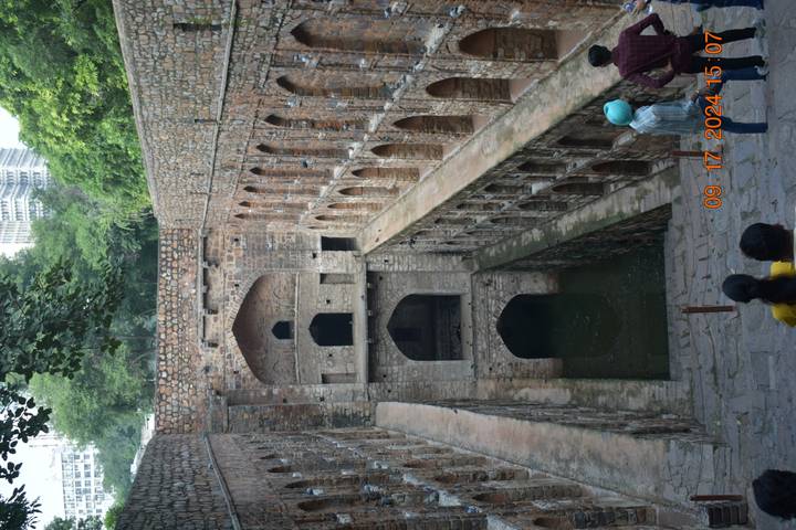 Un puits à degrés historique avec des gens qui l'explorent.