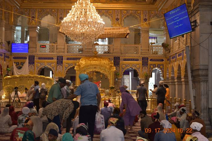 Personnes rassemblées à l'intérieur d'un hall religieux et richement décoré.